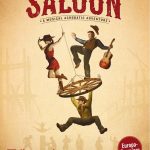 Zwei Cowboys und ein Cowgirl tanzen auf einem Wagenrad, welches als Kronleuchter dient.