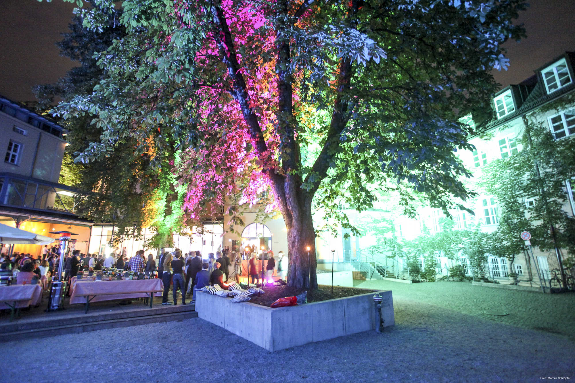 Großer bunt beleuchteter Baum im Innenhof der Praterinsel während einem Firmenevent.