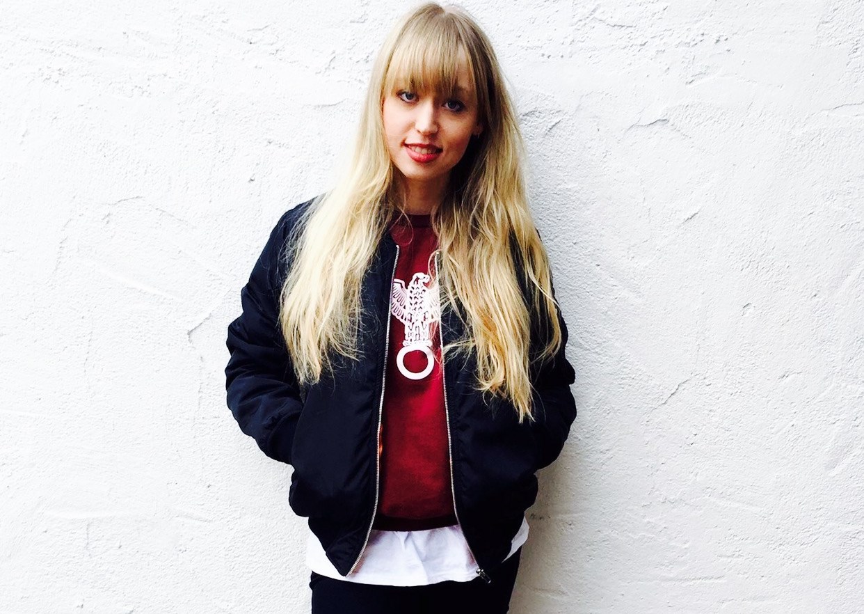 Veronika Bittenbinder mit Bomberjacke vor einer weißen Wand.