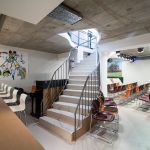 Eine geschwungene Treppe führt hinunter zur Bar im Theatersaal mit Stuhlreihen.