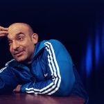 Kabarettist Django Asül lehnt auf einem Stehttisch und denkt nach