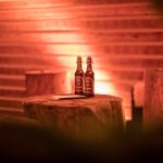 Zwei Bierflaschen mit Bügelverschluss auf einem abgeschnittenen Baumstamm, der als Stehtisch dient.