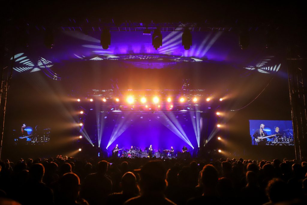 vollblut bietet Produktionsservice, gezeigt wird die Tollwood Musik Arena mit Blick über die Zuschauermenge auf die Bühne. vollblut unterstützt z.B. Konzertproduktionen als lokaler Dienstleister, so stellt die Eventagentur z.B. Mercher*innen für das Toto Konzert in der Musik Arena auf dem Tollwood Sommerfestival.